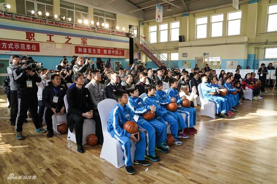 小篮球,大梦想:姚明启动中国少年篮球新篇章 一群身穿红色球衣的小球员们在场边替补席上聚精会神地观看比赛,他们的眼神中充满了对球场的向往和团队荣誉感。
