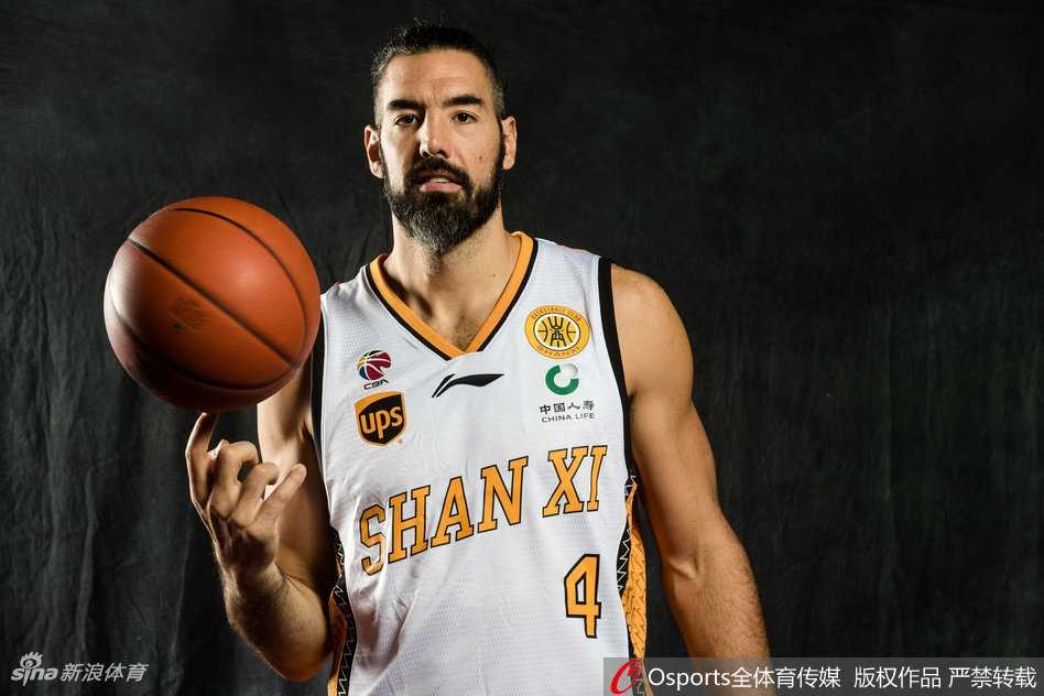 一名山西男篮年轻队员正在进行个人动作写真拍摄，他高高跃起试图完成单手劈扣，身体在空中充分伸展，充满了力量感与爆炸性的视觉冲击。