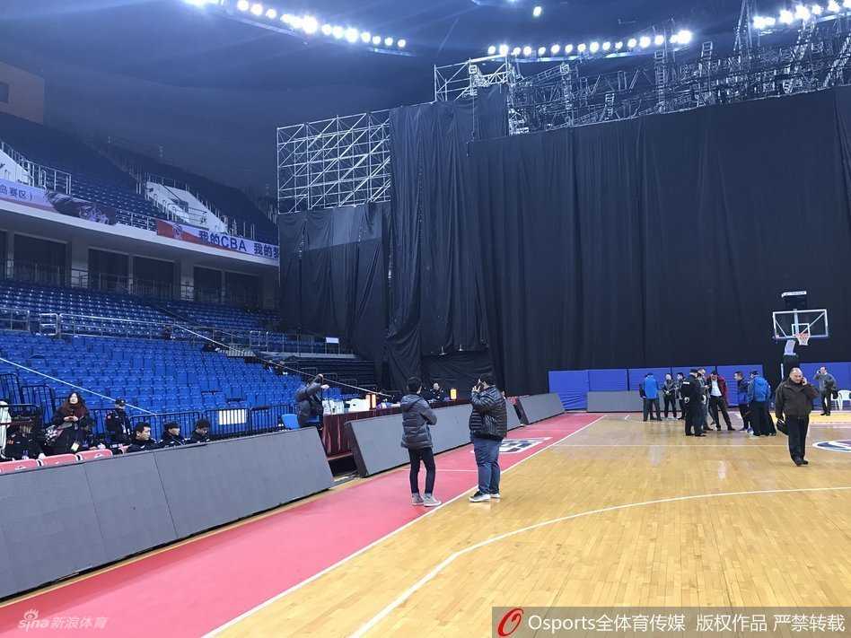 空旷的青岛国信体育馆内，一座为跨年晚会搭建的钢铁舞台占据了篮球场北侧，舞台的金属桁架与篮球架并立，体育馆顶部的灯光照射在场地上，形成了一种比赛与演出交织的奇异景象。