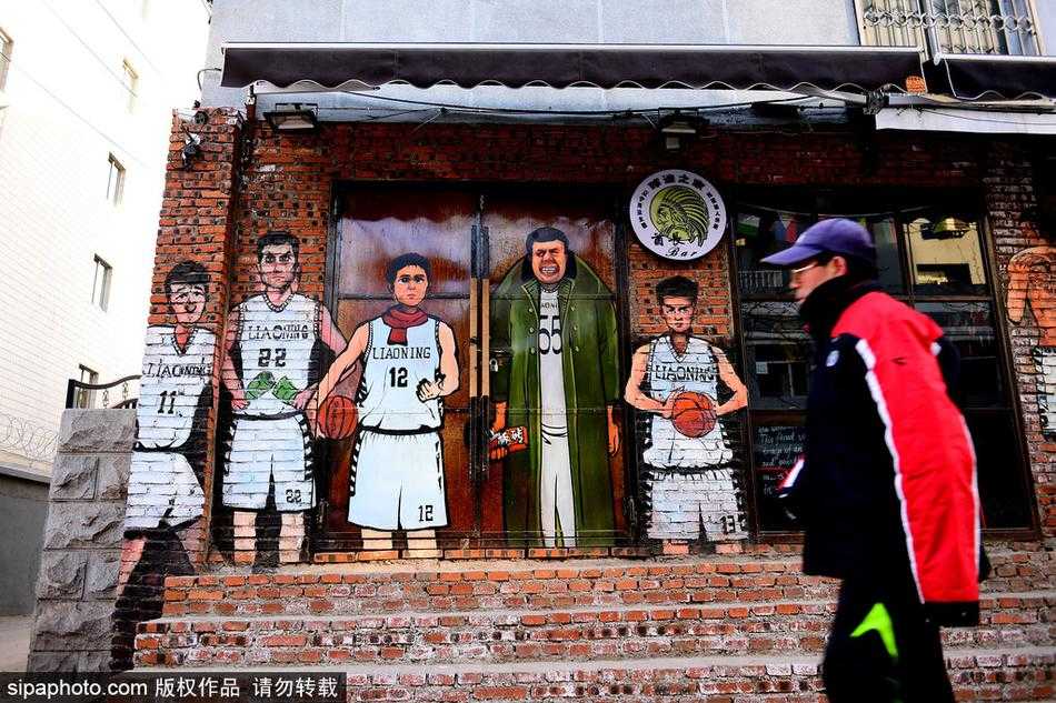 探秘辽篮漫画墙:韩德君板砖在手,杨鸣围脖裹不住的江湖气 沈阳街头,巨幅漫画墙前,身披军大衣的韩德君如同一位扛着板砖的球场老大爷,眼神里写满了“谁与争锋”的霸气。