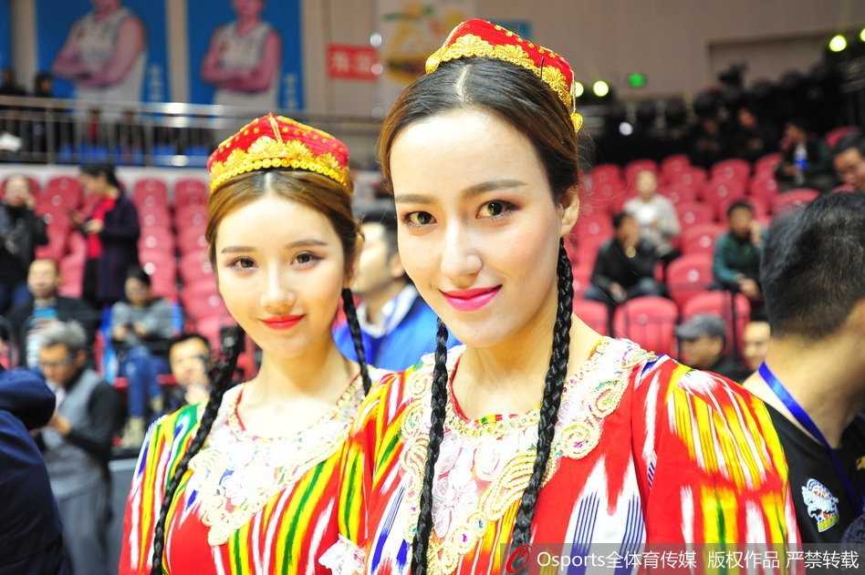 一位拥有深邃眼眸的新疆美女，她身着盛装，在主场灯光的照耀下微笑，精致的五官如同雕刻般立体，瞬间成为全场焦点。