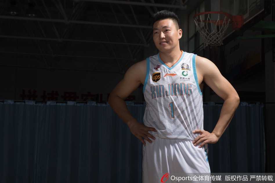 可兰白克-马坎身披新疆队战袍，双手叉腰站立，目光如炬凝视前方，队长袖标在灯光下熠熠生辉，仿佛在无声宣告着守护球队荣誉的誓言。