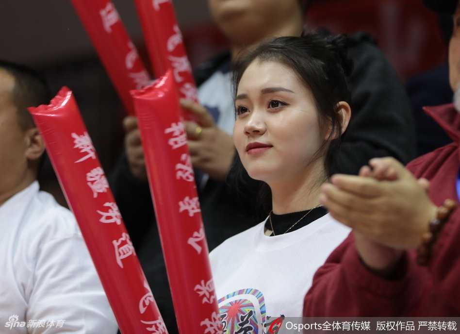 镜头捕捉到一位气质优雅的女球迷，她正用手机记录下赛场上的精彩瞬间，想要留住这一刻的美好。