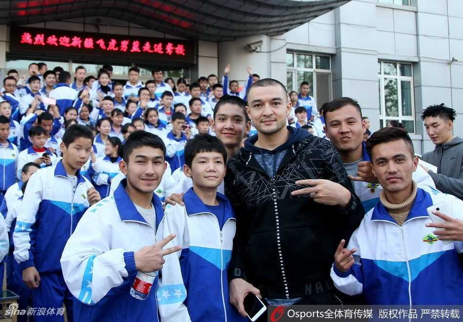 无声世界里的篮球火焰:新疆男篮与聋哑孩子的飞虎情缘 篮球架下,一位新疆男篮球员正弯下腰,手把手地纠正一位聋哑少年的投篮手型。少年仰着头,目不转睛地盯着偶像的手指,眼神里充满了专注与渴望学习的光芒。