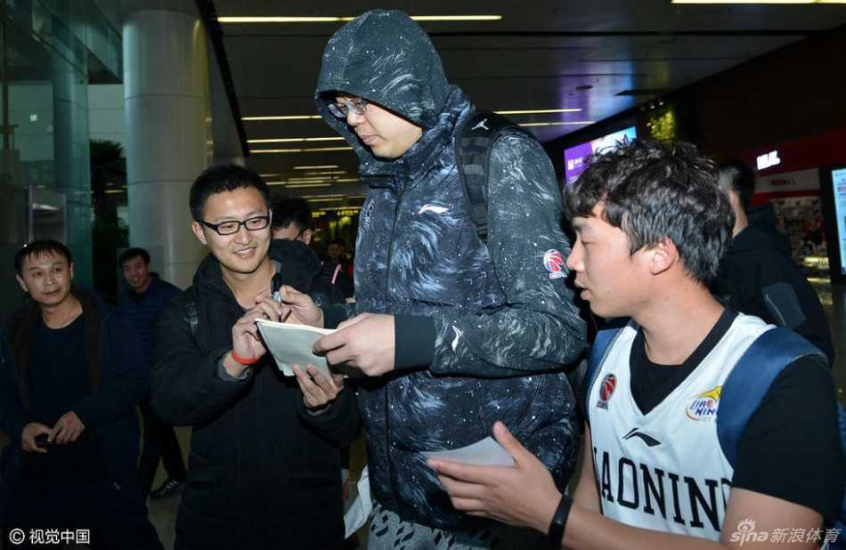 身材魁梧的韩德君被热情的球迷紧紧包围，他手拿一件白色T恤，脸上挂着憨厚而亲切的笑容，耐心地满足着大家签名合影的请求，场面如同巨星见面会。