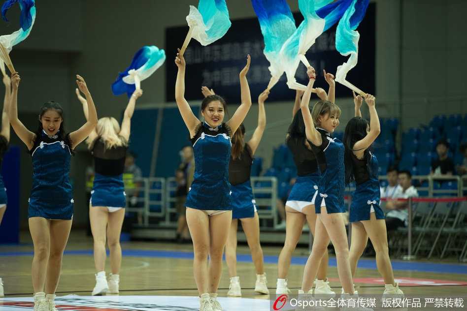 在场地中央，一名笑容甜美的啦啦队员正手持拉花，带领全场观众做起了人浪互动。她极具感染力的笑容通过现场大屏传递给每一个人，仿佛炎炎夏日里的一杯冰镇果汁，让紧张观赛的球迷们得到了短暂的放松与愉悦。