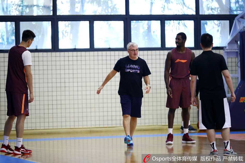 广东宏远全队在进行放松拉伸，夕阳透过窗户洒在球员们身上，映照出一张张坚毅而充满信心的脸庞。