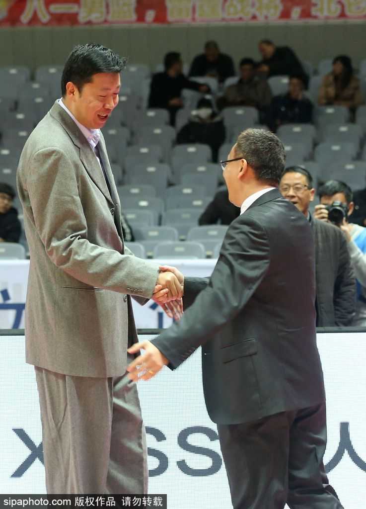 镜头拉近，捕捉到了两人交谈中最真挚的表情。范斌微微低头，眉头轻蹙，正对着大郅娓娓道来，仿佛在分享着执教福建队的心得与困惑。王治郅的面容依然俊朗温和，嘴角带着淡淡的笑意，耐心地聆听这位老大哥的诉说，两人周围仿佛形成了一个独立于喧嚣赛场之外的安静世界。