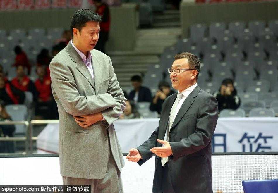 在宁波雅戈尔体育馆明亮的灯光下，身披福建队教练组服饰的范斌与八一队助教王治郅相对而立，范斌伸手指向场内，神情专注地讲述着什么，而王治郅则双手抱胸，微微侧耳倾听，眼神中流露出对老队友的无比信赖。