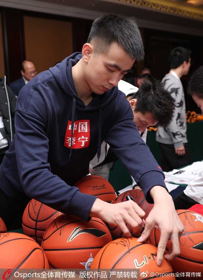 在签名台的另一端，一位身穿白色外套的球员正俯身为球迷手中的大幅海报签名，他的神情极为认真，手中的笔尖划过纸张，留下清晰的墨迹，这一刻球星与球迷的距离被无限拉近。