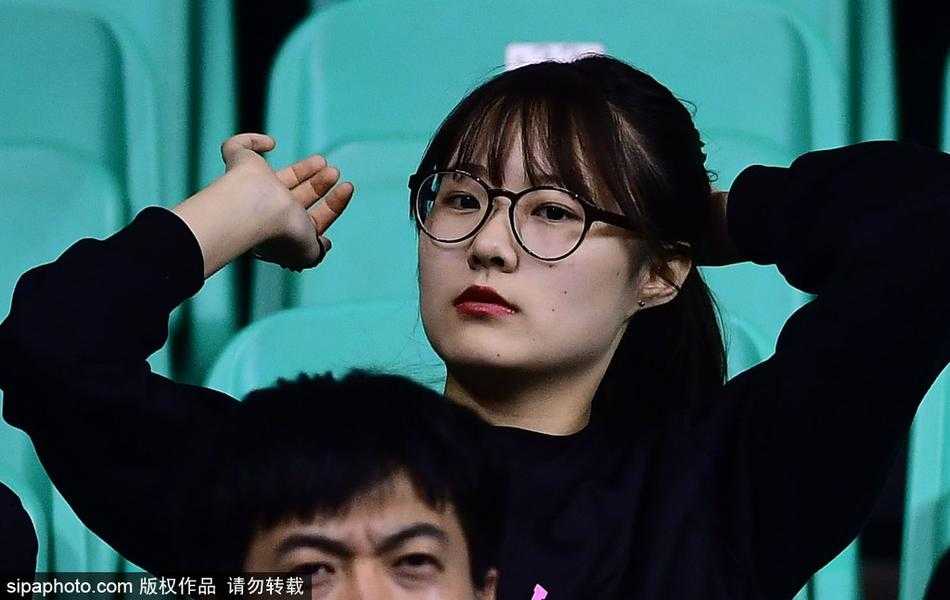 女孩拿着手机面带微笑，背景是正在退场的球员通道，她依然不舍得离开座位，那一抹彩虹色仿佛定格了2017年寒冬里最温暖的球迷瞬间。