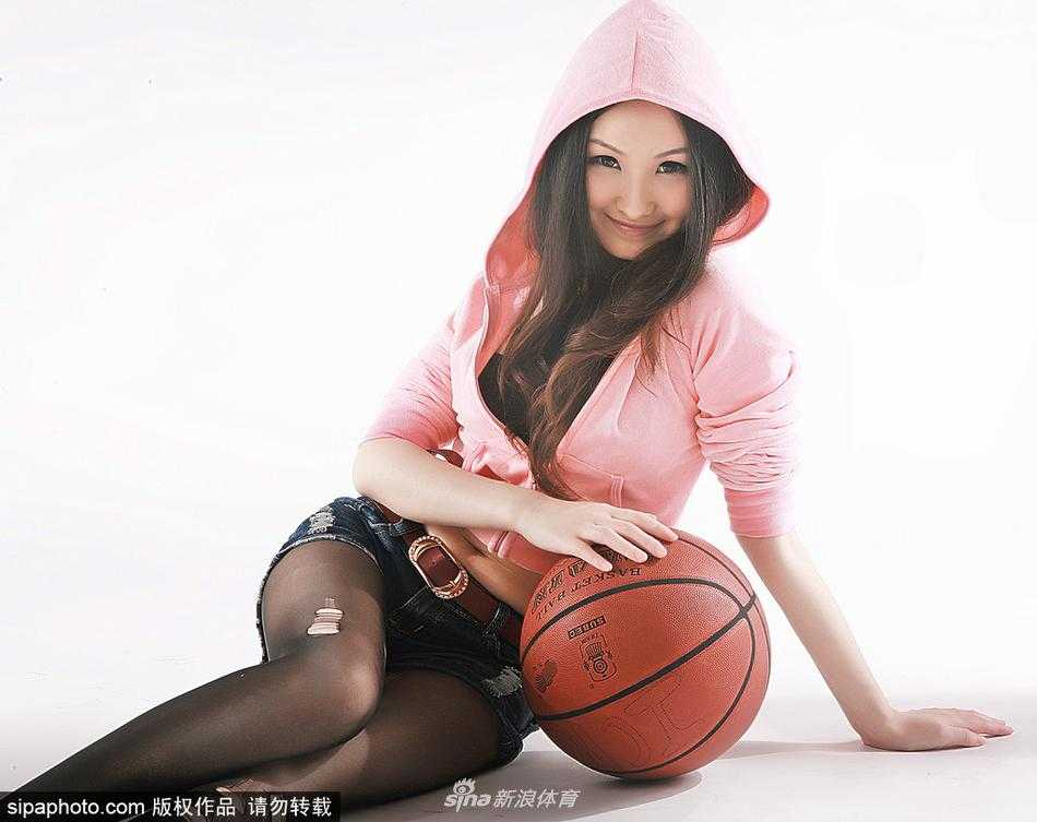 杨乃霏侧身倚靠在篮球架旁，轻轻撩动秀发，宽松的运动背心下摆微扬，不经意间展露被丝袜包裹的修长美腿，姿态既俏皮又充满魅力。