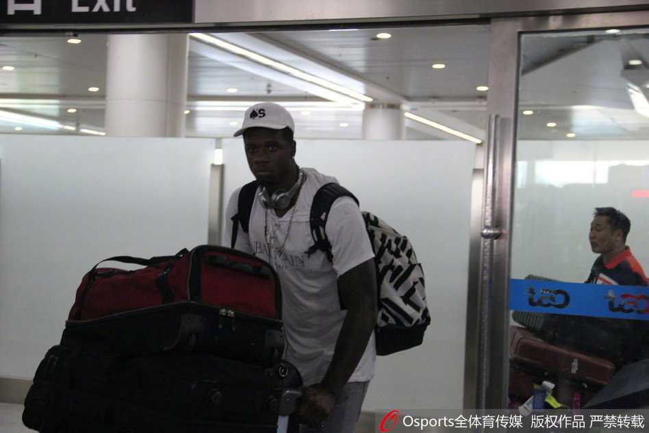 从行李提取处走出的琼斯，面带微笑与前来接机的工作人员握手，身旁的母亲目光温柔地注视着这一切。