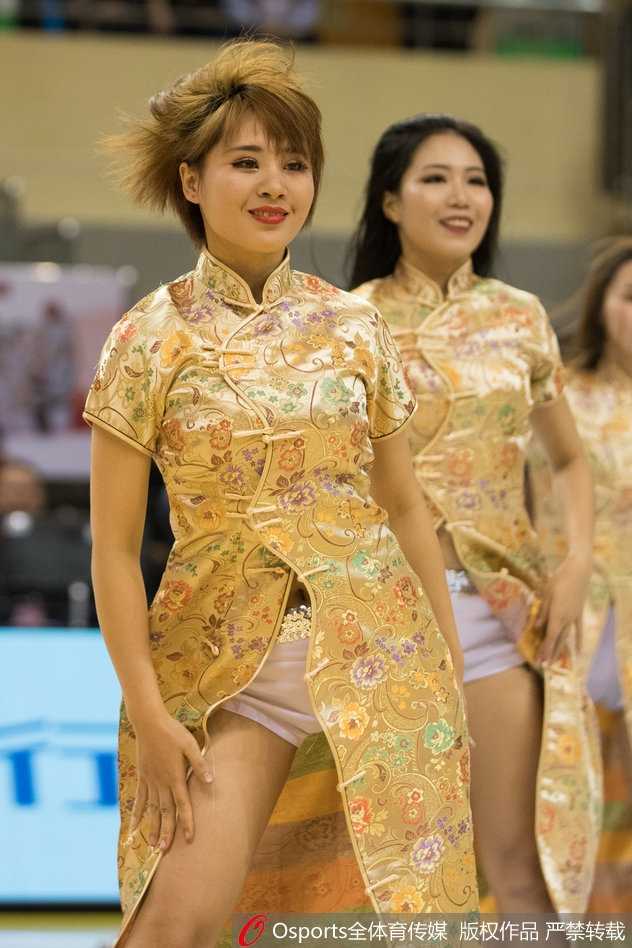 特写镜头下，一位篮球宝贝双手高举金色花球，眼神自信地看向前方，脸上的妆容精致，皮肤在灯光下显得格外白皙