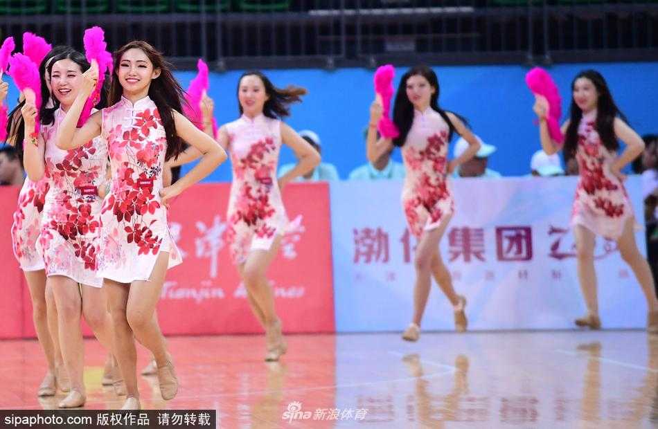 津门旗袍宝贝舞动全运赛场 篮球架起传统文化与体育桥梁 几位身着水墨晕染风格旗袍的宝贝们面带灿烂笑容,在球场中央排开舞步,裙摆随着动作轻盈飘动,与身后巨幅国旗背景相得益彰。