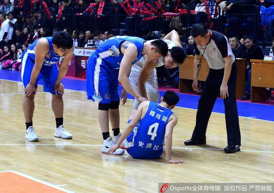 史鸿飞在拼抢后痛苦倒地，双手紧捂受伤部位，表情因剧痛而扭曲，一旁的江苏队队友焦急地低头查看他的伤情。
