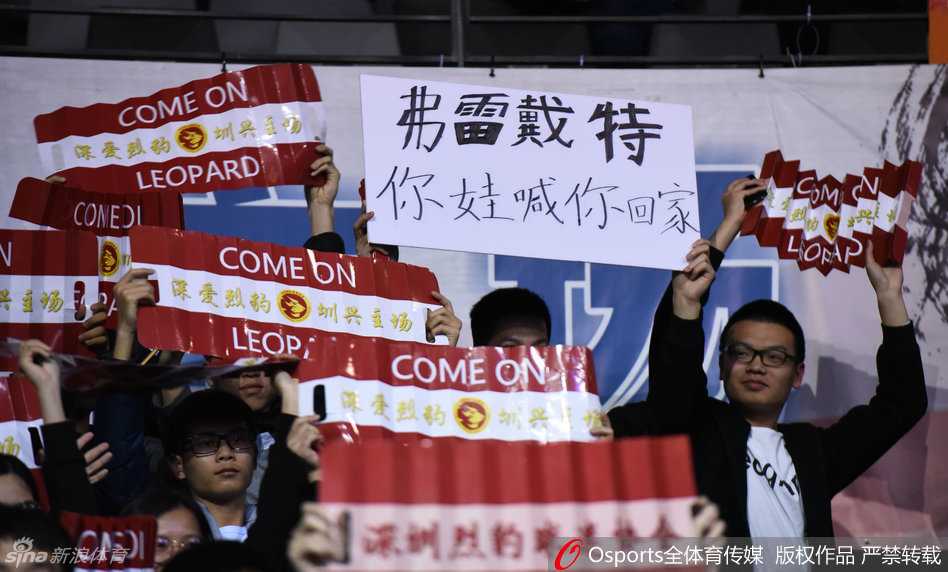 比赛进入白热化阶段，全场球迷起立，一位戴着眼镜的斯文球迷也忍不住振臂高呼，他手中挥舞的围巾上写着‘深圳’，将个人情感与城市荣耀紧密相连。