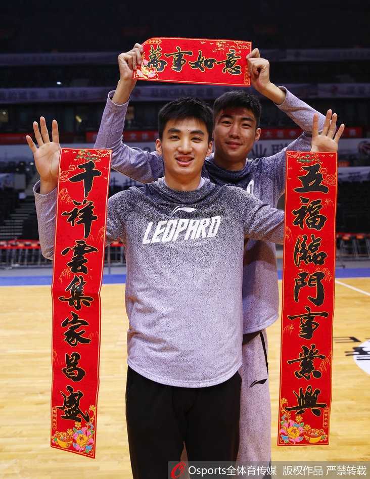 深圳烈豹新春献瑞 孟铎领衔拜年大片重温篮球热血 深圳男篮队长孟铎在喜庆的红色背景下,双手紧握鼓槌奋力敲响铜锣,眼神中充满坚定与笑意,仿佛在为即将到来的新春敲开胜利之门。