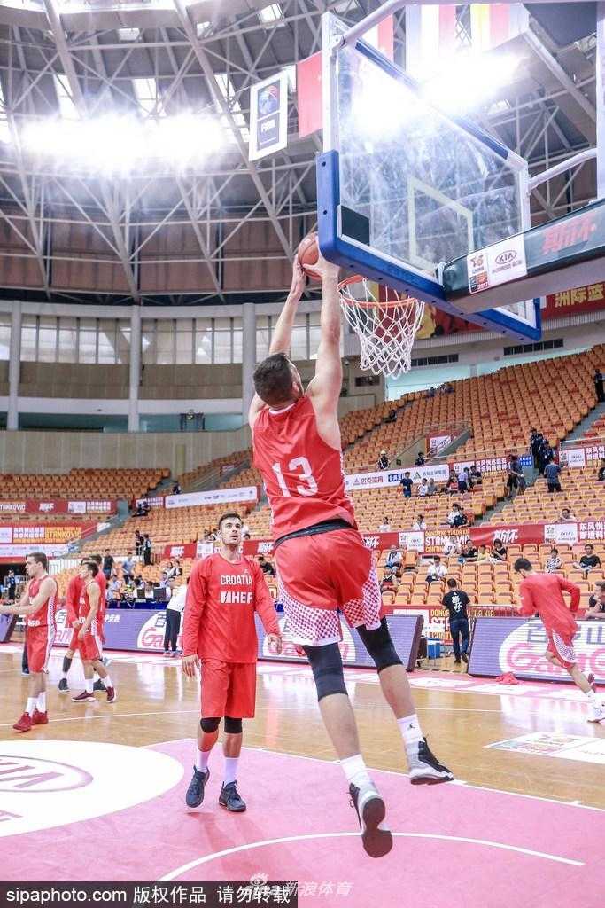 深圳雨夜静备战 克罗地亚青年军斯坦科维奇杯蓄势待发 克罗地亚队球员在深圳体育馆进行赛前热身,他眼神专注,高高跃起试图封堵队友的投篮,场馆顶棚的灯光映照在球员们汗水闪烁的肩膀上,大战前夕的紧张感在空气中弥漫。