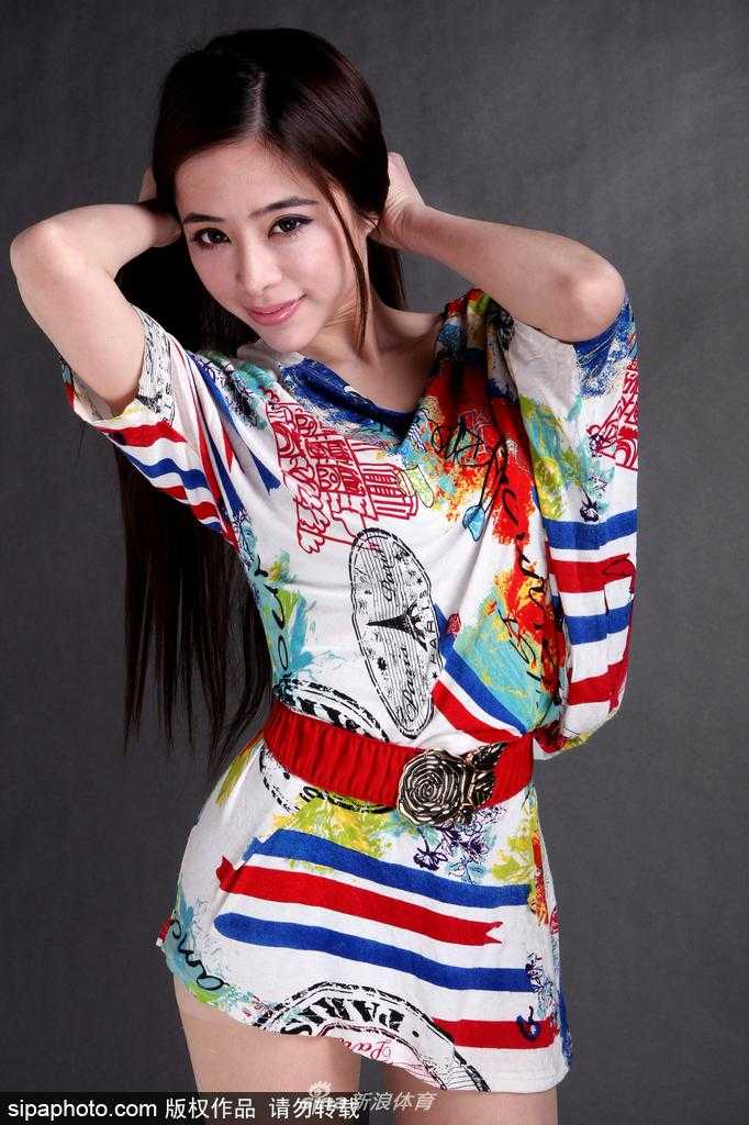 袁颖芬站在球场边，身穿简约的运动背心和短裤，身形高挑修长，沐浴在阳光中仿佛自带光环