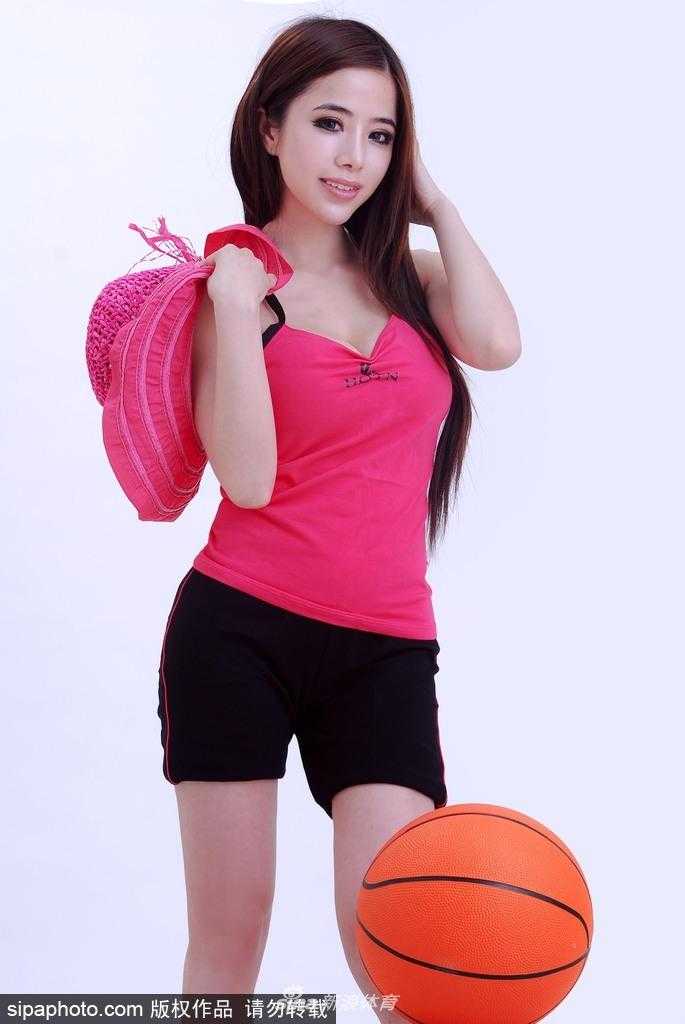 袁颖芬身穿亮色运动套装坐在场边，修长双腿自然舒展，脸上洋溢着明媚自信的微笑