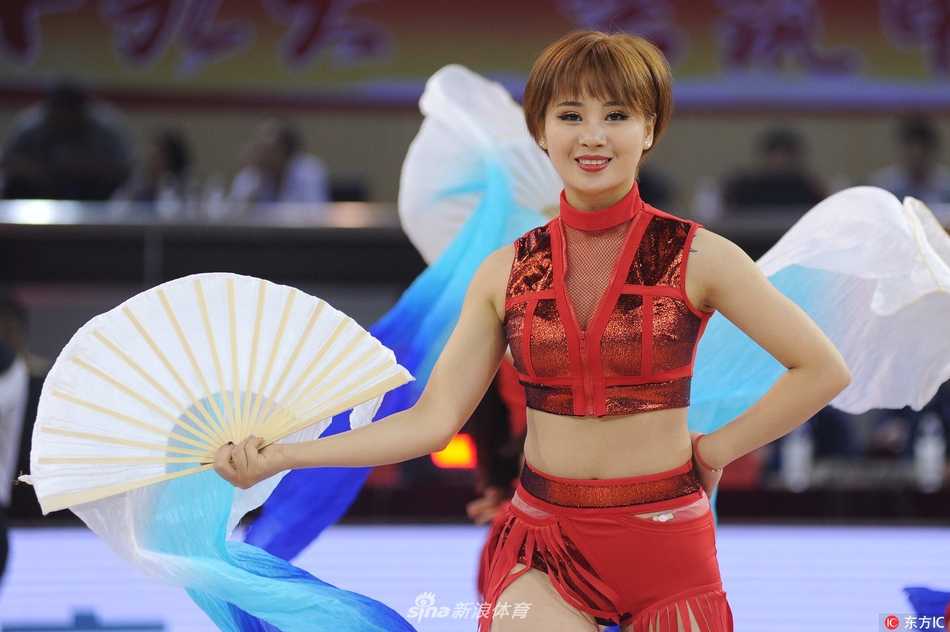 溧阳奥体中心热力绽放 啦啦宝贝舞动CBA季前赛 啦啦宝贝正在表演高难度的舞蹈动作,她身体后仰展现出极佳的柔韧性,手中的花球如同流星般在灯光下留下璀璨的光影,现场气氛被推向高潮