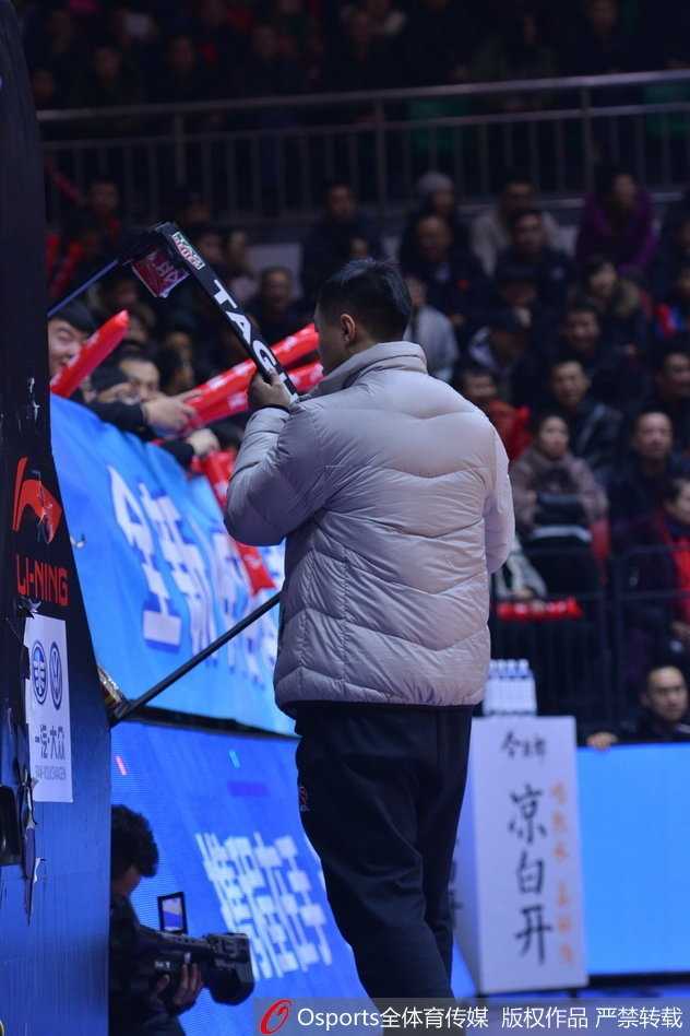 裁判正在向技术台比划手势解释刚才的冲突，身后的记分牌外壳裂痕累累，现场气氛剑拔弩张，这一幕成为了本场比赛最令人难忘的瞬间之一