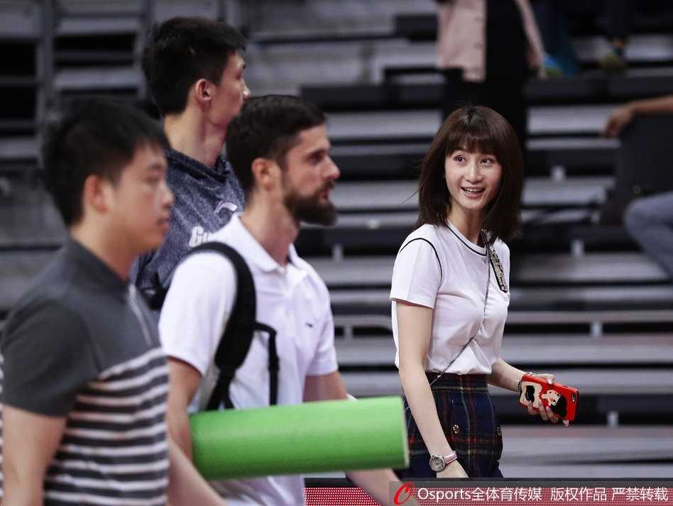 身着时尚休闲装的周鹏妻子刘小美现身看台，高挑的身材和甜美的笑容在人群中格外亮眼，正用手机记录着丈夫在场上的每一个瞬间