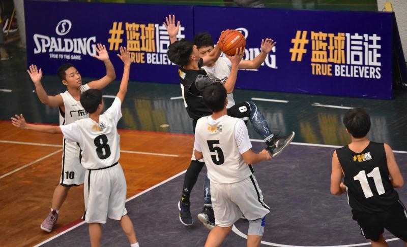 云山学校两名队员在禁区筑起铜墙铁壁，他们高高跃起，伸展长臂，用坚决的封盖试图阻挡对手的强力上篮，眼神中透出绝不退让的坚毅。