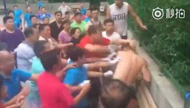 在围观群众的注视下，几名年轻人试图与情绪激动的大爷大妈们理论，肢体语言充满无奈与戒备，场面混乱不堪。