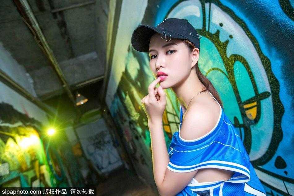 只见这位篮球宝贝身姿挺拔，双手轻轻扯住球衣边缘，脸上洋溢着自信明媚的笑容，仿佛在与看台上的球迷进行着充满活力的互动。