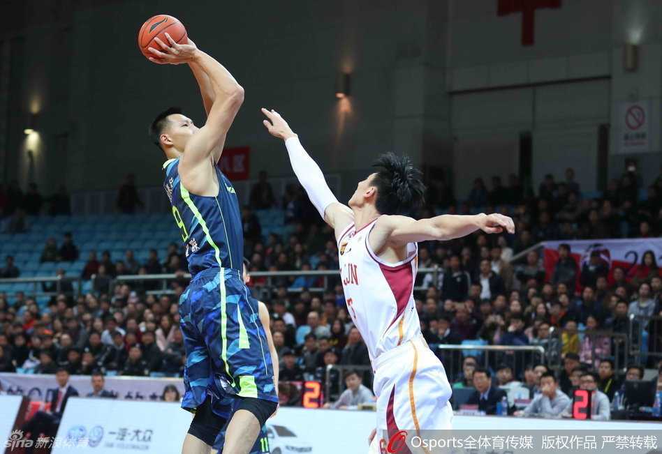 易建联迎着防守者高高跃起，手腕柔和拨出篮球，篮球在空中划出完美弧线