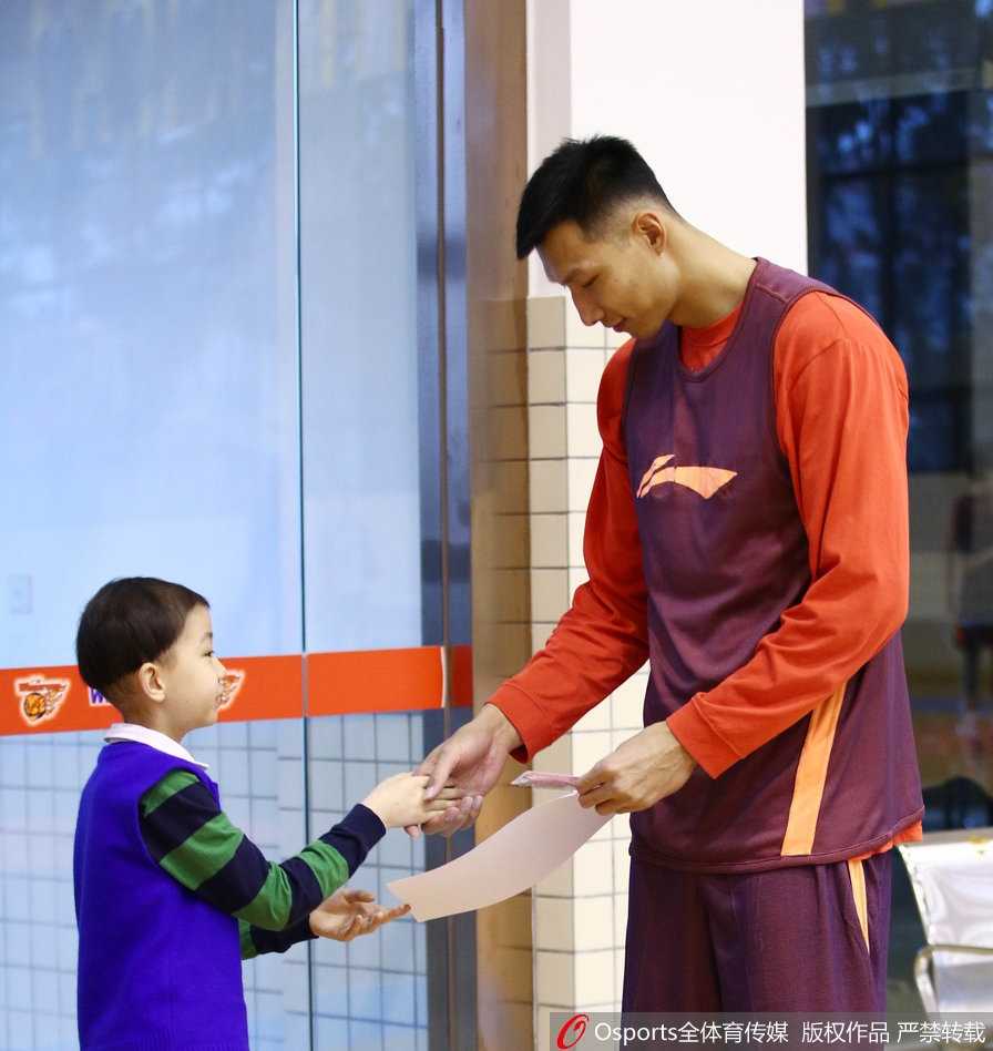 肿瘤男孩轩轩的CBA圆梦之旅:在广东宏远感受篮球的温暖与力量 轩轩手持签名篮球,与身穿训练服的广东宏远队员面对面交流,队员俯身倾听轩轩说话,画面温馨感人。