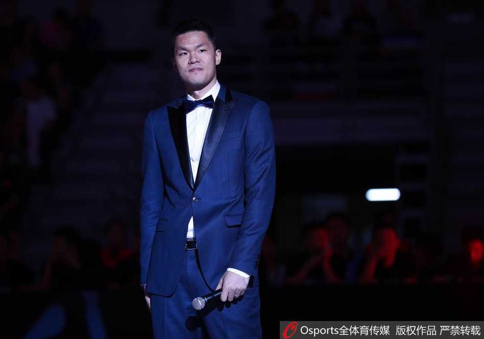 站在球场中央进行致辞的朱芳雨，手持话筒，神情专注而真挚，背后是坐无虚席、为他欢呼的球迷，他用幽默的话语感谢了所有人，为这段球员生涯画上完美句号。