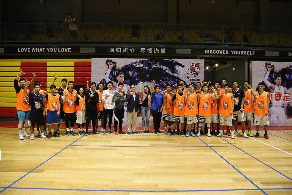 一名球员在三分线外高高跃起，手腕轻柔拨球，篮球旋转着飞向篮筐，背景是湛蓝的天空和稀疏的云朵，整个画面充满飘逸的美感。