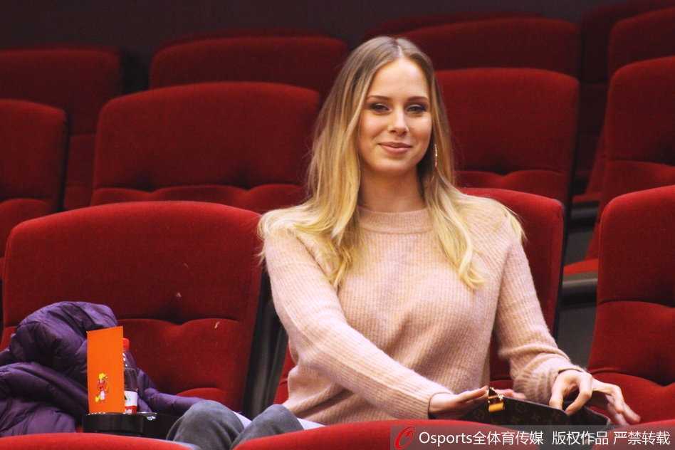 宝莲娜在比赛关键时刻紧张地攥紧了双手，身体微微前倾，仿佛要用自己的意念帮助丈夫在场上命中每一个关键球。