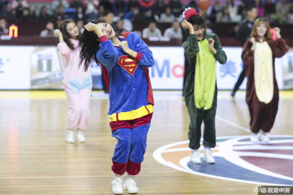 一名篮球宝贝穿着搞怪的恐龙连体衣，做出“起飞”的姿势，旁边的伙伴则模仿着开枪的动作，仿佛在玩“我们都是神枪手”的游戏，场面欢乐无比。