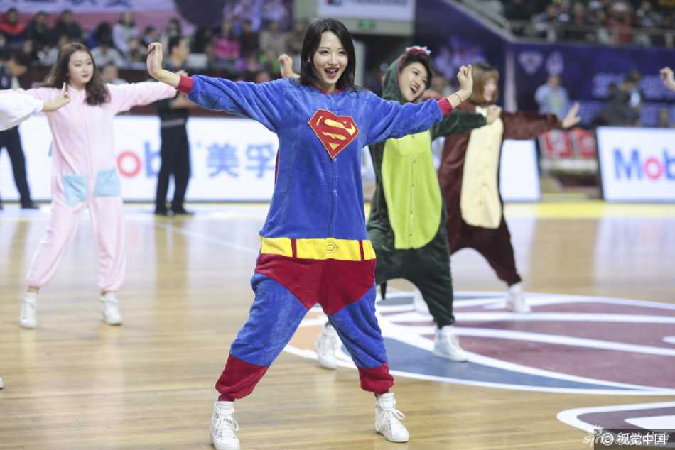 一位穿着红色超人披风睡衣的篮球宝贝，正对着镜头握拳鼓劲，眼神里带着还没睡醒的迷糊，却又努力做出严肃的表情，滑稽又可爱。