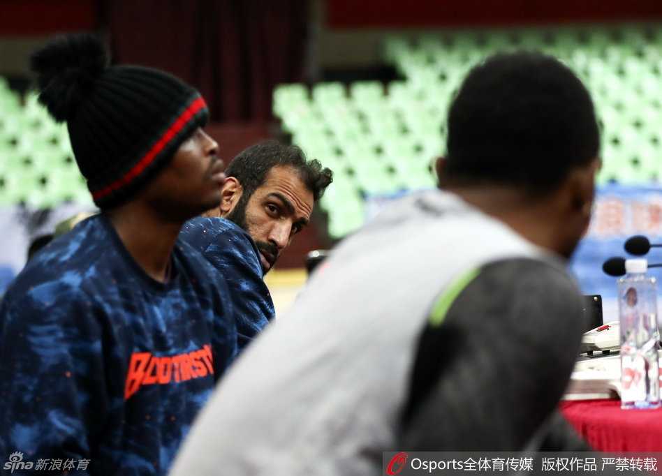 主教练杨学增拿着战术板双手比划着对球员们大声训话，队员围成一圈神情严肃认真聆听