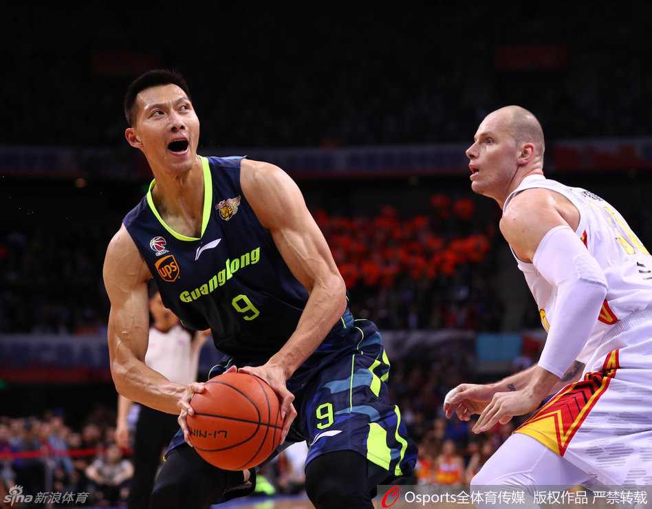 易建联完成一次漂亮的投篮后，眼神坚定地望向篮筐，嘴角露出一丝不易察觉的坚毅，身后的队友正挥舞毛巾为他欢呼