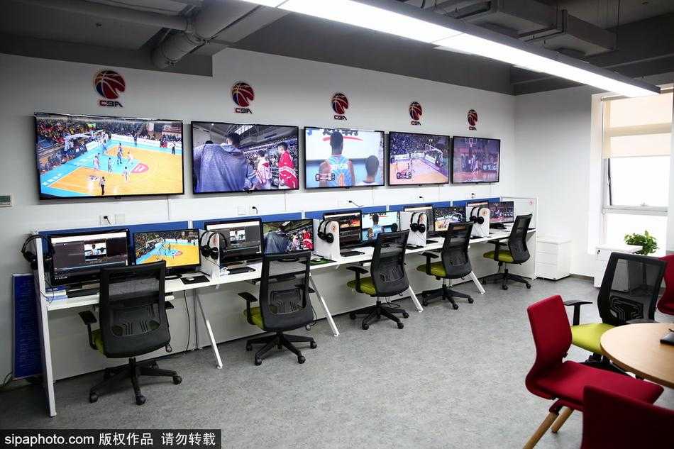 一名工作人员正在调试复杂的音频通讯设备，确保回放中心与各个赛场之间的沟通线路畅通无阻。