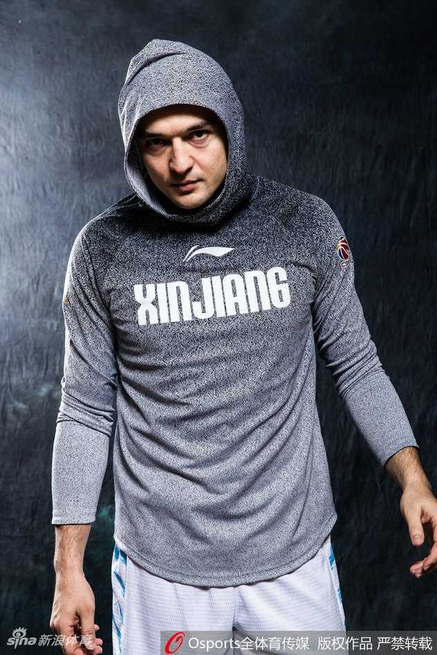 西热力江室内特写，暖光勾勒出他棱角分明的面庞，眼神坚定地望向一侧，背景虚化凸显出赛前的专注与宁静