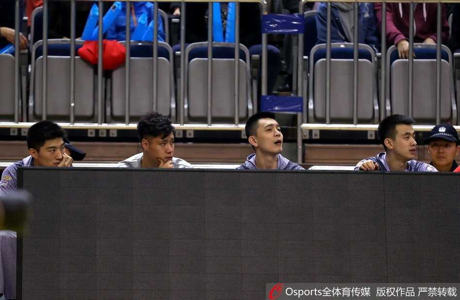 贺天举身穿休闲外套双手插兜，在场边目睹队友投中三分