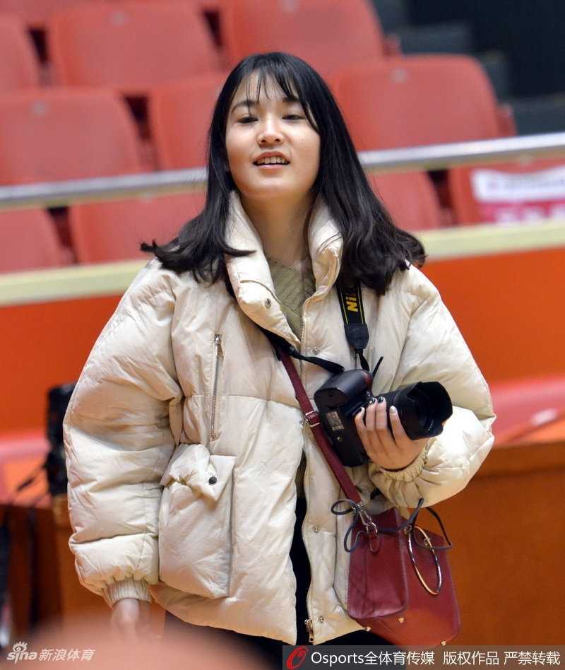 特写镜头中，美女记者正低头检查刚才录制的采访素材，夕阳的余晖透过训练馆的玻璃窗洒在她身上。她手中的录音笔和笔记本，见证了这一天高强度工作的累累硕果。