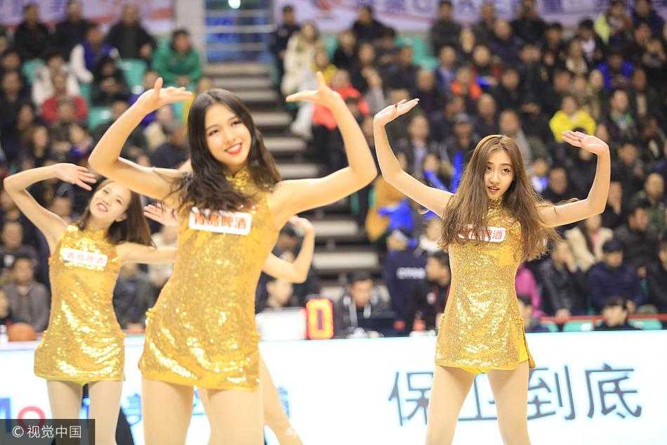 全体拉拉队员背对镜头排成一列，金色短裙和修长美腿构成一幅动感的画面，她们正全情投入地为稍显沉寂的赛场注入活力。