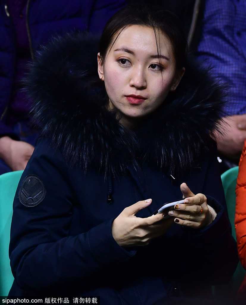 镜头拉近，这位戴着黑框眼镜的知性美女在人群中格外显眼。她微微侧身，嘴角扬起一抹恬淡的微笑，似乎在和朋友讨论着刚才场上发生的激烈对抗，那份从容与优雅与球馆内的喧嚣形成了一种奇妙的反差。