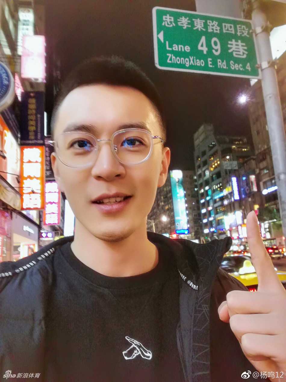 辽篮队长杨鸣与队友刘志轩等人在台湾的夜色下合影，大家身着便装，姿态悠闲，背景的灯火映衬出兄弟间的情谊与旅途的惬意。