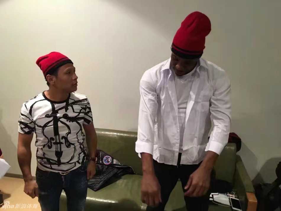 郭艾伦身穿绿色时尚风衣，一脸得意地站在中间，左右手分别搂着哈德森和宋小宝，三人对着镜头露出大白牙，画面十分有爱。