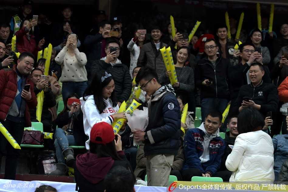 幸福的女孩踮起脚尖，为单膝跪地的男友送上深情的吻。周围的球迷纷纷举起手机，记录下这篮球与爱情完美交织的经典瞬间，整个体育馆都沉浸在幸福的海洋中。