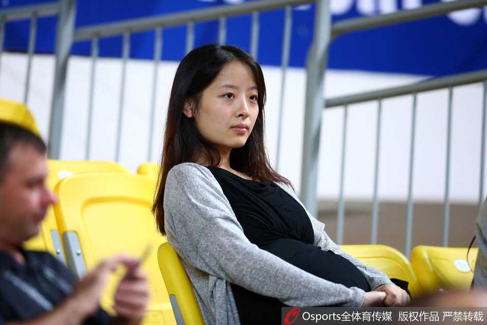 妻子在场边静静凝视，背景是喧嚣的球场和模糊的记分牌，这一刻仿佛世界都安静了，只剩下她眼中那个在场上奔跑的55号身影。